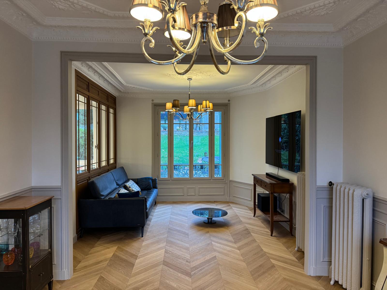 Séjour avec canapé, fenêtre sur le jardin et parquet en point de Hongrie